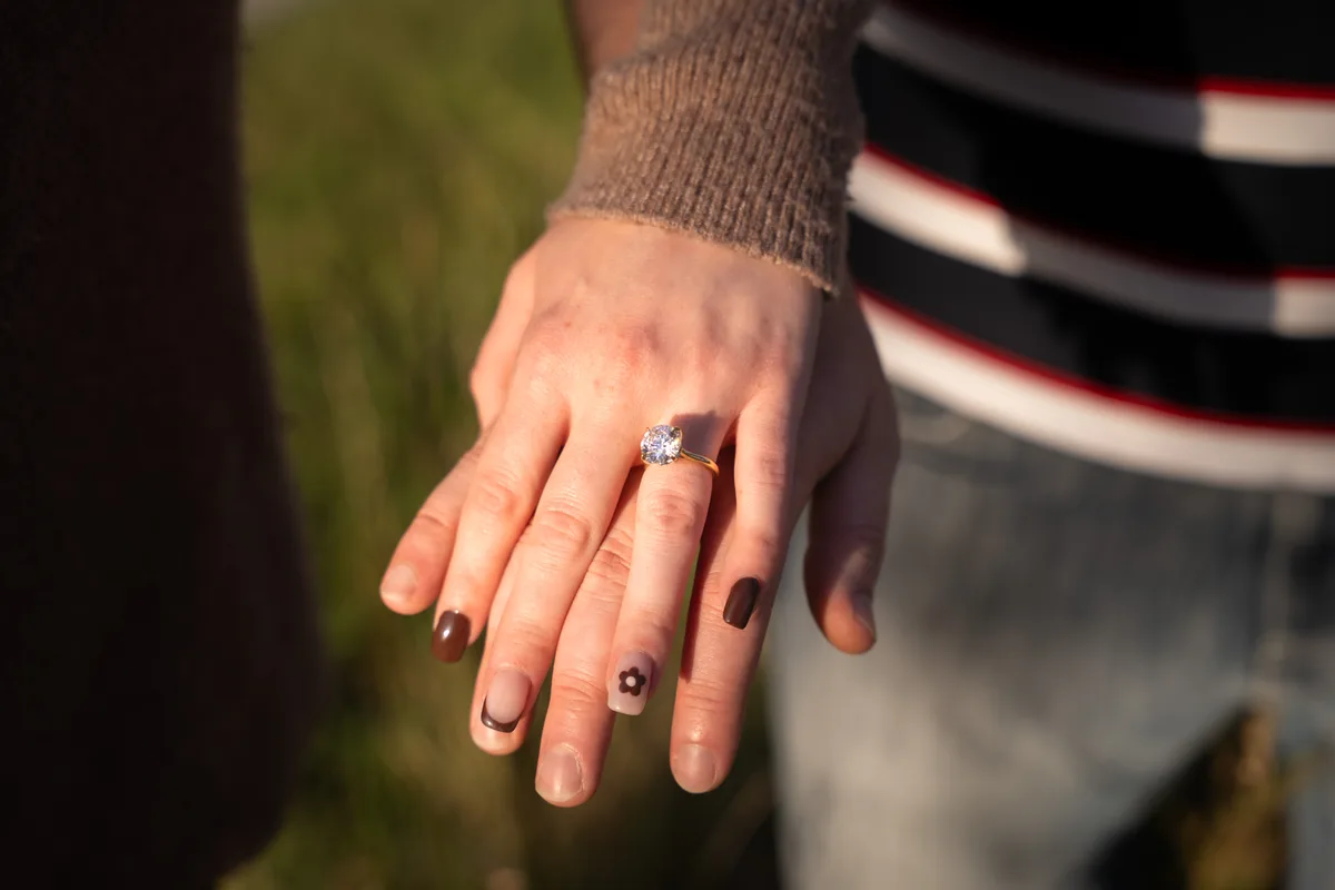 Close detail of the engagement ring on her hand resting against his chest, Mahoney State Park, Nebraska